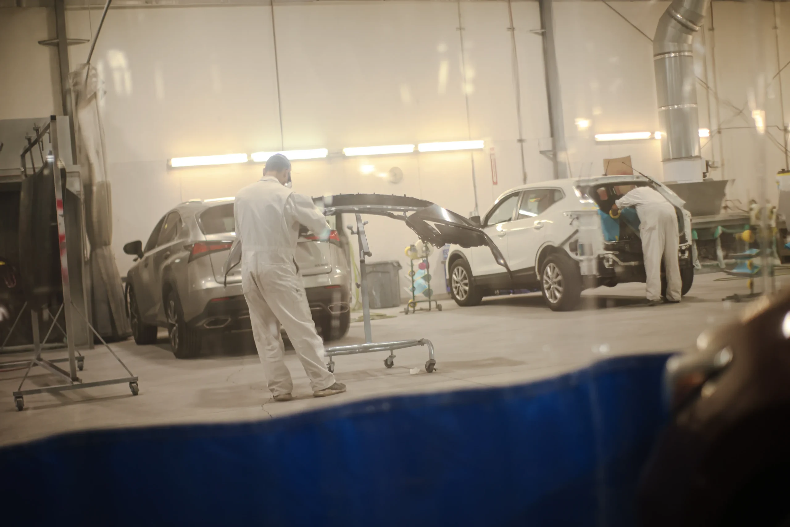 Auto body technician spraying a bumper inside Tacoma paint booth